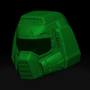 Puede incluir: Un casco verde impreso en 3D con una visera y un diseño detallado. El casco tiene una superficie texturizada y un aspecto futurista.