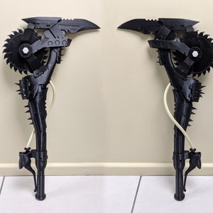 Könnte beinhalten: Eine schwarze, im 3D-Druck hergestellte Waffe mit einer Kreissäge, einer Klinge oben und einem Griff mit einem stacheligen Design. Die Waffe steht aufrecht auf einem weißen Fliesenboden.