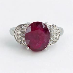 Ruby and white Topaz ring on 925 sterling band.  Marked S925, 3 Carat Oval Lab ruby stone.