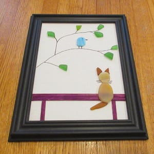 Beautiful sea glass art picture with cat on a bench watching a bird in a tree made into a great picture  with nice colors that you will love