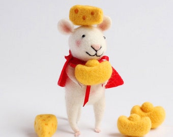 Op de afbeelding: Een witte viltmuis met een rode cape houdt een gouden munt in zijn pootjes. De muis heeft een gele kaas op zijn kop en er liggen drie andere gele kaasmuntjes op de tafel.