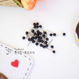 May include: A pile of black headed pins with silver needles. The pins are scattered on a white surface. The text "Easy Handmade.  宝 手 作 &middot; 原创 系列" is visible in the image.