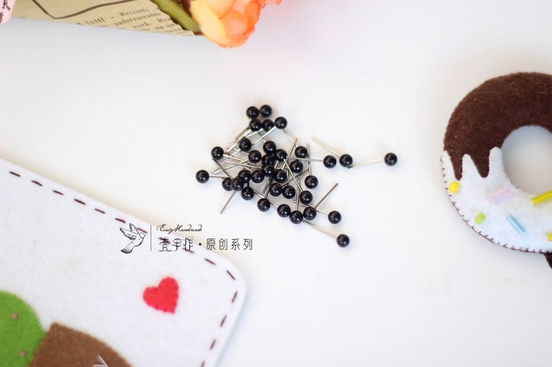 May include: A pile of black headed pins with silver needles. The pins are scattered on a white surface. The text "Easy Handmade.  宝 手 作 &middot; 原创 系列" is visible in the image.