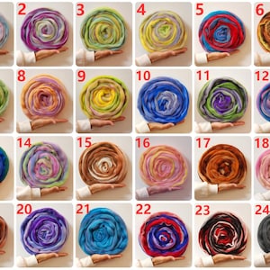 May include: Twenty-four skeins of yarn in various colors and patterns, arranged in a grid. Each skein is rolled up and held in a hand.