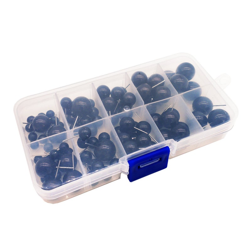 May include: A clear plastic storage box with a blue latch, filled with black plastic-headed push pins. The push pins are organized in rows in the box.