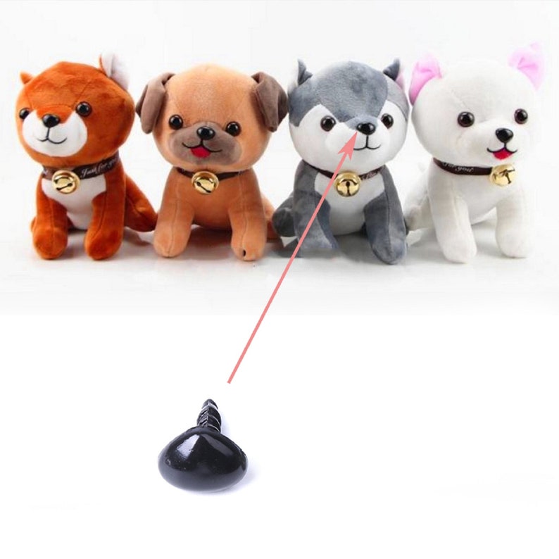 May include: Four plush toy dogs with black safety eyes. The dogs are brown, gray, white, and orange. The dogs are sitting on a white surface. A black plastic safety eye is shown below the dogs.