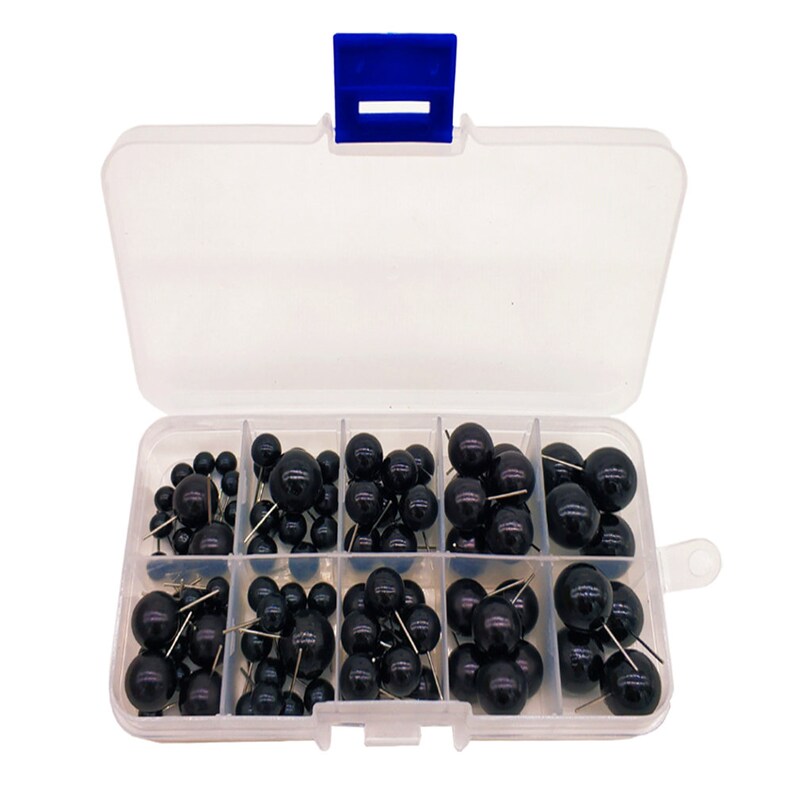 May include: A clear plastic storage box with a blue lid containing black push pins with round heads. The box has eight compartments, each filled with push pins.