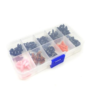 May include: A clear plastic storage box with multiple compartments filled with various colors of plastic safety eyes for crafts. The box has a blue latch.