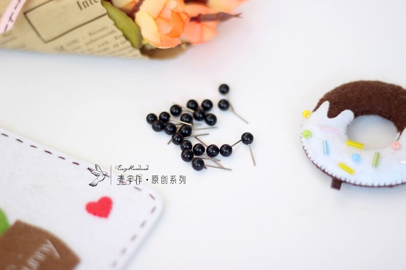 May include: A close-up of a collection of black push pins with silver metal heads. The pins are scattered on a white surface. The text "Easy Handmade,  童 手作り &middot; 原创 系列" is visible in the lower left corner of the image.