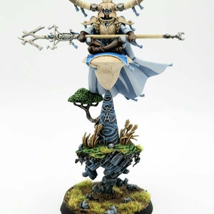 May include: A detailed miniature figure of a fantasy character. The figure is seated and holds a staff, with a horned helmet and flowing robes. It is perched atop a floating island with a small tree and grassy terrain, all set on a circular base.