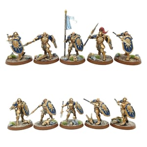 May include: Ten gold and blue painted miniature figures of warriors with swords and shields. The figures are standing on round bases.