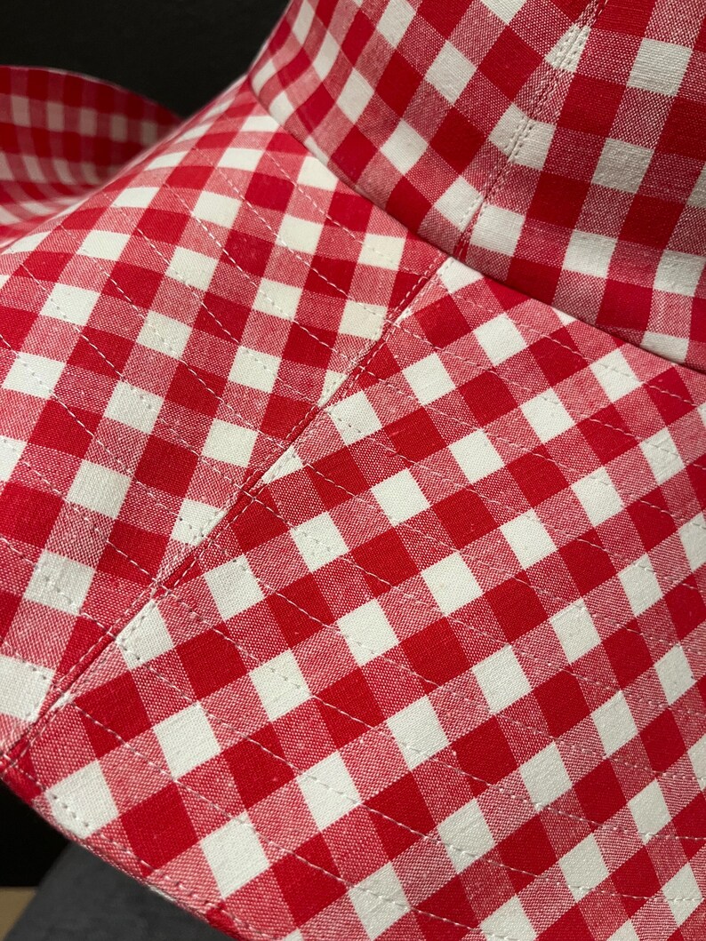 K&ouml;nnte beinhalten: Nahaufnahme eines rot-wei&szlig; karierten Hutes. Der Stoffhut hat ein klassisches Vichy-Muster. Die N&auml;hte sind sichtbar und der Hut scheint gut verarbeitet zu sein. Ein Sommeraccessoire.