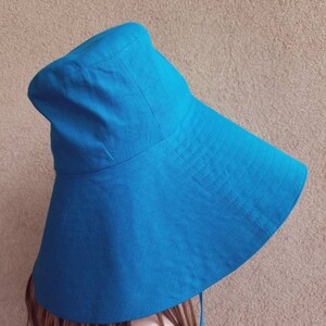 May include: A wide-brimmed sun hat in a vibrant blue color. The hat is made of a soft, lightweight fabric and has a simple, classic design.