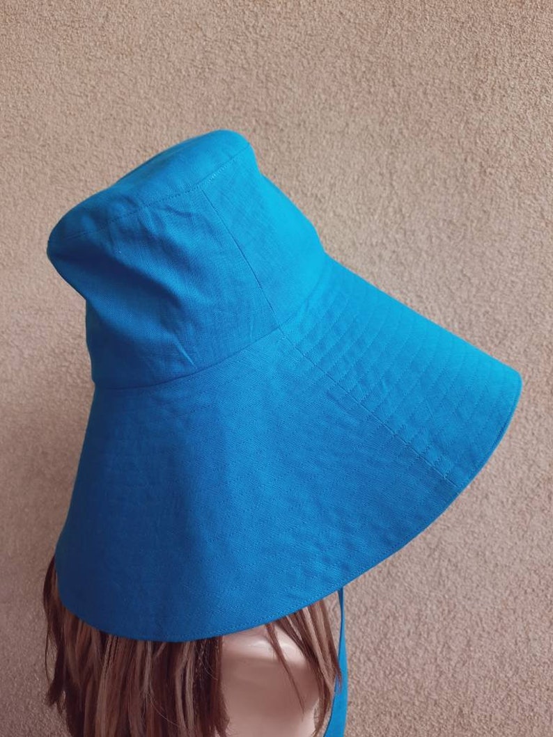 May include: A wide-brimmed sun hat in a vibrant blue color. The hat is made of a soft, lightweight fabric and has a simple, classic design.