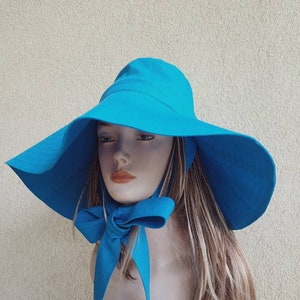 May include: A wide-brimmed sun hat in a bright turquoise blue. The hat has a large bow tied at the back.