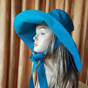 May include: A wide-brimmed sun hat in a vibrant turquoise blue. The hat has a large brim and a matching ribbon tied at the back of the neck.