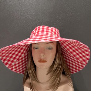 K&ouml;nnte beinhalten: Ein Sonnenhut mit breiter Krempe und einem rot-wei&szlig; karierten Vichy-Muster. Der Hut hat eine gro&szlig;e Krempe und ein klassisches, sommerliches Design. Ein stilvolles Accessoire f&uuml;r Outdoor-Aktivit&auml;ten.