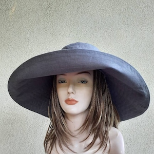 May include: A wide-brimmed hat made of a soft, gray fabric. The hat has a large, flat brim and a simple, rounded crown.