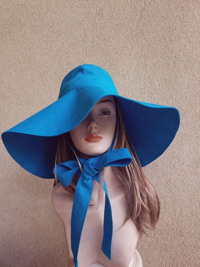 May include: A wide-brimmed sun hat in a bright blue color. The hat has a large brim and a matching blue ribbon tied at the neck.
