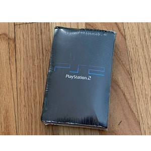 May include: A black PlayStation 2 console box with the PlayStation 2 logo and text on the front.