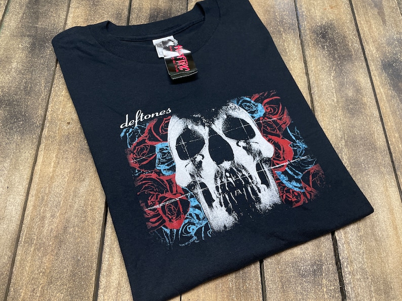 May include: Black t-shirt with a white skull graphic and red and blue roses. The text "Deftones" is printed on the shirt.