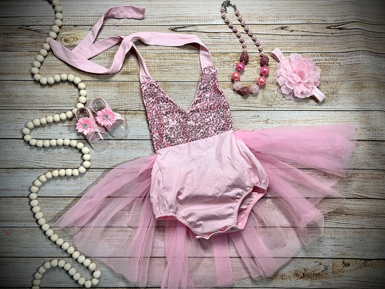 Puede incluir: Conjunto de beb&eacute; ni&ntilde;a rosa con corpi&ntilde;o de lentejuelas, falda de tul, diadema con flor rosa y collar de cuentas rosas.