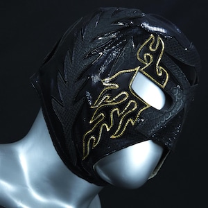 May include: Black wrestling mask with gold flame design. The mask has a textured, snake-skin like pattern.