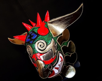 May include: A green, red, gold and blue lucha libre wrestling mask with a bull's horns and a fierce expression.