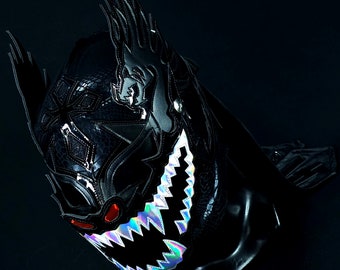 May include: A black wrestling mask with a detailed design featuring a dragon and sharp teeth. The mask has a red eye and iridescent accents.
