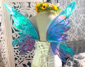 May include: A pair of iridescent blue and purple fairy wings with a white corset. The wings are made of a clear plastic material and have a delicate, intricate design.