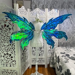 May include: A pair of iridescent blue and green fairy wings with a white corset. The wings are made of a translucent material and have a delicate, intricate design.
