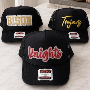 May include: Three black trucker hats with mesh backs and foam fronts. One hat features the word BISON in gold glitter, one features the word Trojans in yellow embroidery, and one features the word Knights in red glitter with a silver outline.