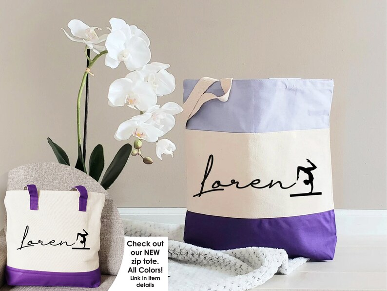 May include: Two canvas tote bags with purple accents. The larger bag has a lavender top, a white middle section with the name "Loren" and a gymnast silhouette, and a purple bottom. The smaller bag has a white middle section with the name "Loren" and a gymnast silhouette, and a purple bottom.