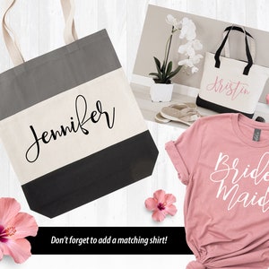 May include: Two tote bags with personalized names, "Jennifer" and "Kristin", and a pink t-shirt with the text "Bridesmaid" in white. The bags are black and white striped with a gray top. The t-shirt is a soft pink.