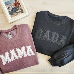 May include: Two sweatshirts, one maroon with "MAMA" in white lettering and one black with "DADA" in white lettering. Both sweatshirts have a distressed, vintage look.