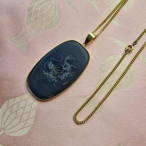 May include: A gold chain necklace with a black oval pendant featuring a white dragon design.