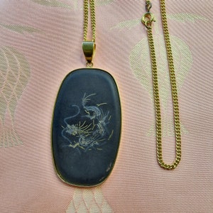 May include: A gold chain necklace with a black oval pendant featuring a white dragon design.