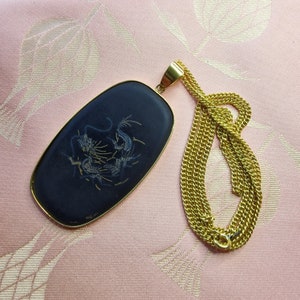 May include: A gold chain necklace with a black oval pendant featuring a gold dragon design.