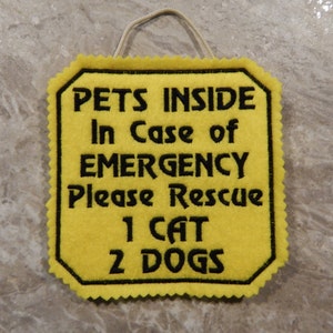 Bright yellow felt sign embroidered with PETS INSIDE In case of EMERGENCY Please Rescue 1 CAT 2 DOG in bold letters with black thread. 
Has yellow felt on the back with paracord for hanging. Edges are done with pinking shears. Size approx. 5x5 square