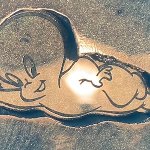 Könnte beinhalten: Ein schwarz-weißes Cartoon-Gespenst mit einem schelmischen Grinsen liegt auf der Seite. Das Gespenst ist in dunkelgrau umrandet und vor einem hellgrauen Hintergrund platziert.