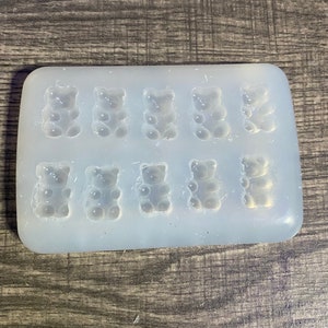 Könnte beinhalten: Eine transparente Silikonform mit neun bärenförmigen Vertiefungen. Die Form ist zum Herstellen von Gummibärchen oder anderen kleinen Leckereien gedacht.