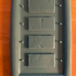 May include: A teal blue silicone mold with four rectangular cavities for making soap or resin crafts.