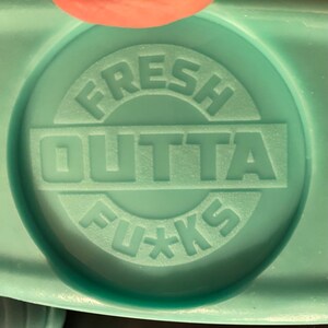 May include: A turquoise blue silicone mould with the words "FRESH OUTTA FU*KS" embossed in white.