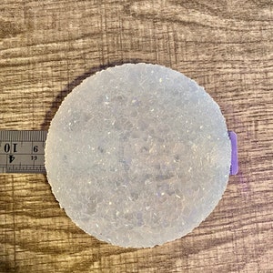 Pode incluir: Um coaster redondo, transparente e translúcido com uma superfície texturizada. O coaster tem aproximadamente 7,5 cm de diâmetro.