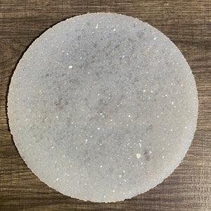 Puede incluir: Un posavasos redondo blanco con una textura moteada. El posavasos está hecho de un material ligero y poroso.