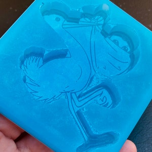 May include: Blue silicone mould with a detailed outline of a cartoon bird wearing a mask. The bird is standing on one leg and has its wings spread out.