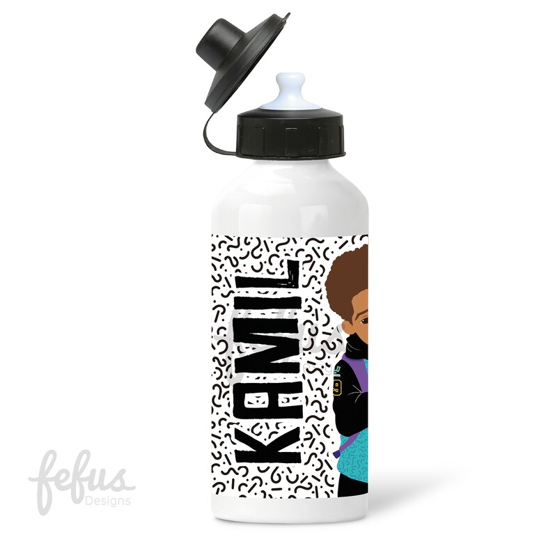 May include: White water bottle with a black lid and a black and white geometric pattern. The bottle has a cartoon illustration of a young boy with a backpack and the name "Kamil" printed in black.