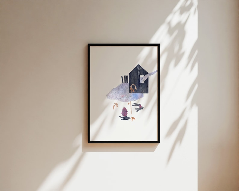 May include: Framed art print featuring a whimsical illustration. The artwork depicts a stylized house with a bird, a campfire, and other abstract elements. The print is framed in a black border and hangs on a neutral-colored wall.