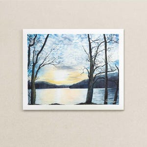 May include: Watercolor painting of a serene lake scene at sunset. Bare trees frame the water, with a soft, golden light reflecting on the lake's surface. The sky is a mix of blue, white, and yellow hues.