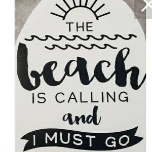 May include: White sign with black text that reads "THE BEACH IS CALLING and I MUST GO." The design includes a sun, waves, and a banner. The sign is a decorative item.